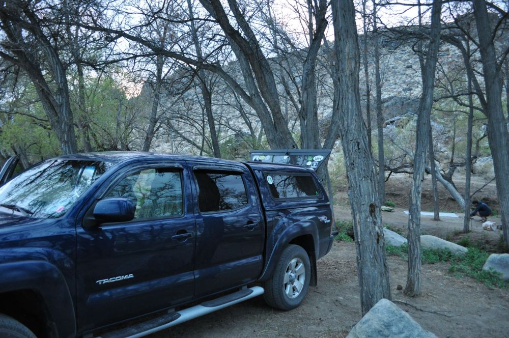 Arno crouches to prepare the spot for our tent, between the two small branches of the creek.