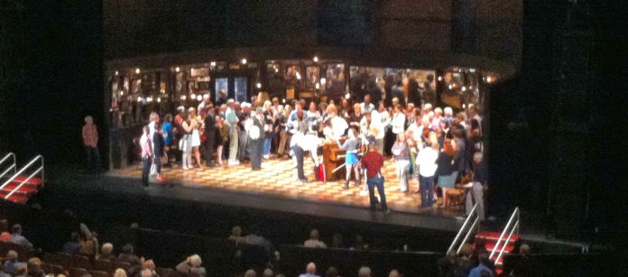 Pre-show performance of Once, with audience members onstage enjoying live music from the actors.