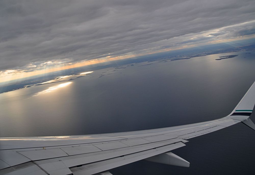 Plane banks as we head toward the Boston bay. Crepuscular rays light up the shoreline like an invitation.