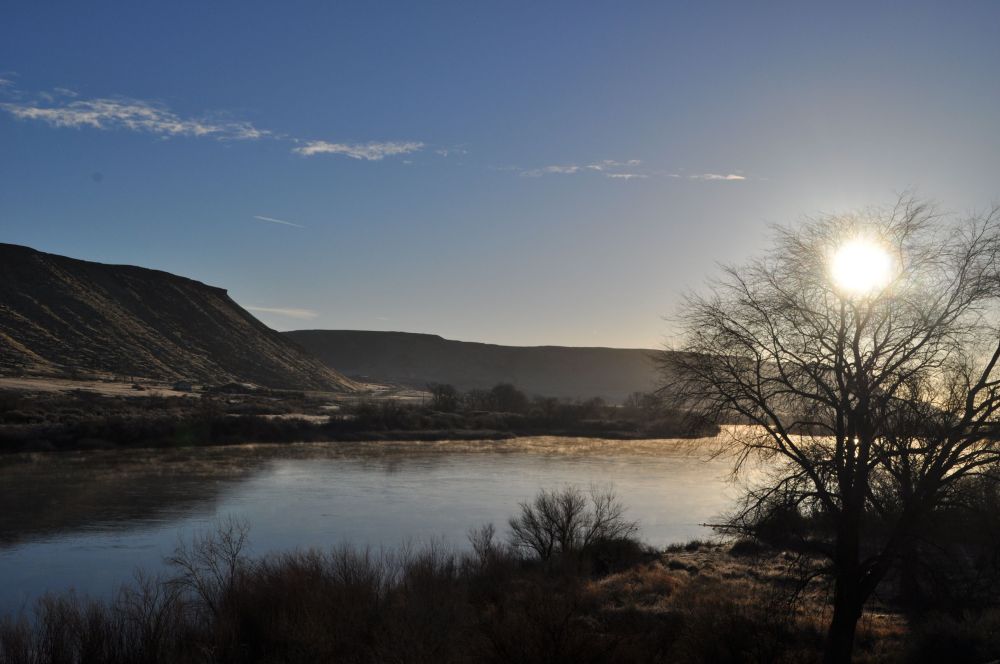 Warm rays of the sun strike the surface of the Snake River, creating a frosty winter mist.