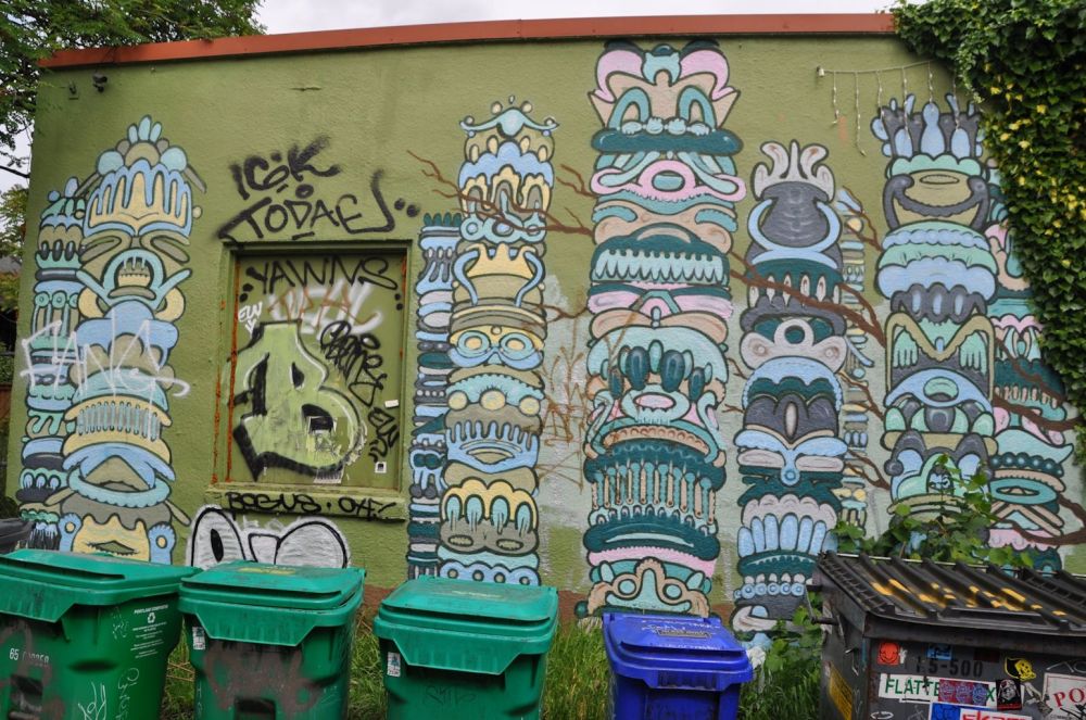 I get a total charge out of this one. The artwork makes me think of Mayan writing on columns. I can't tell if it was intentional, but each column is stacked "on top" of the recycling bins.