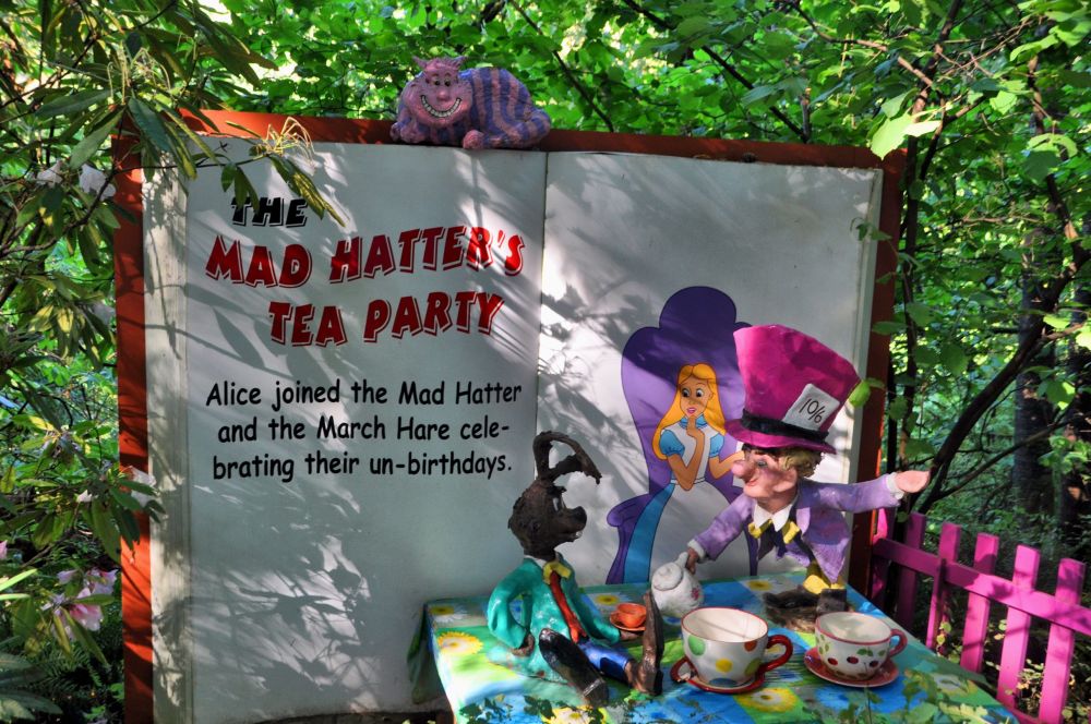 Mad Hatter and March Hare have tea, while the Cheshire Cat looks down, grinning