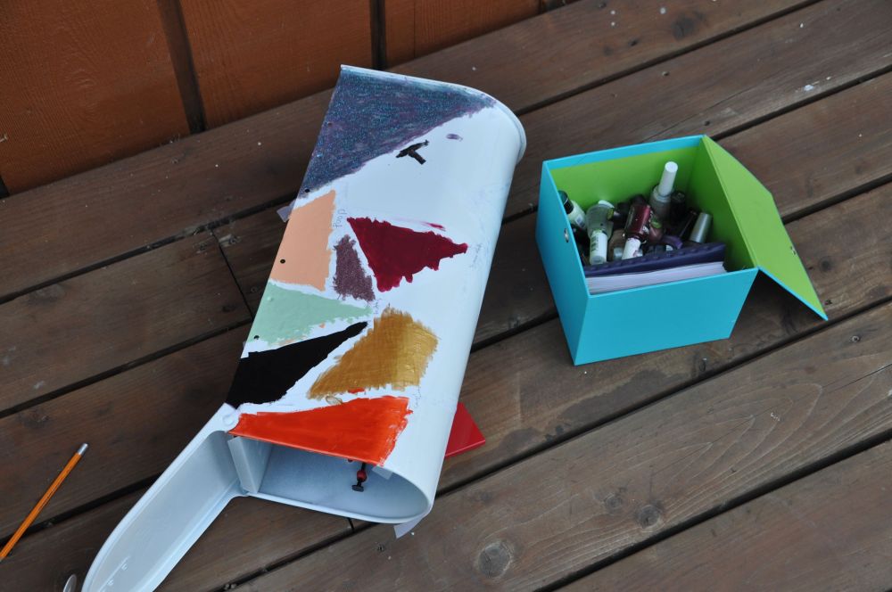 Partially painted mailbox with a collection of nail polish handy.